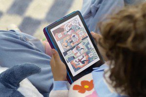 A child holding a color Kindle Colorsoft e-reader with the display on.