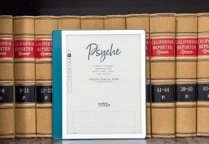 The Kindle Scribe in front of a bunch of books sitting on a shelf.